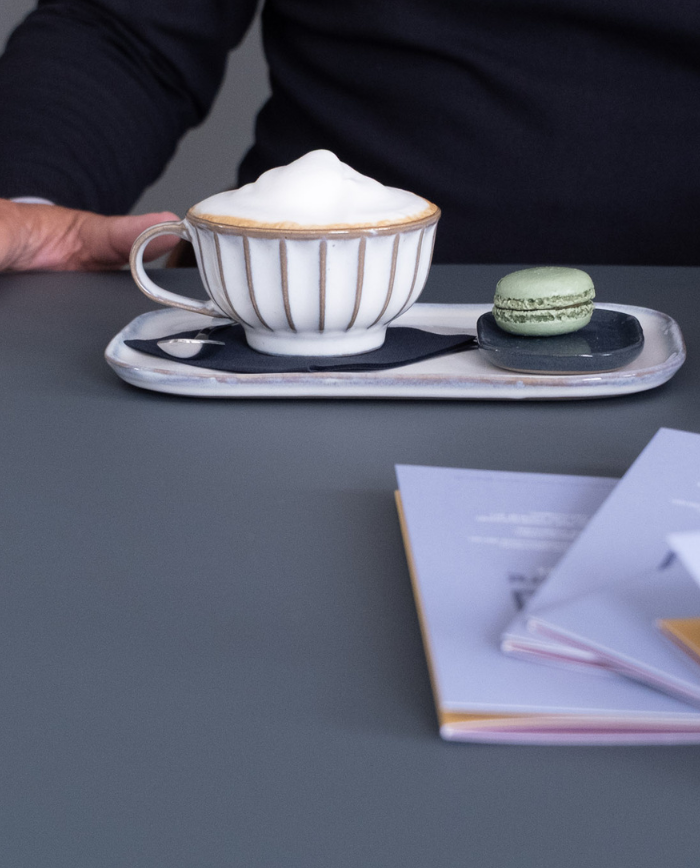 Hand in beeld met een cappucino.